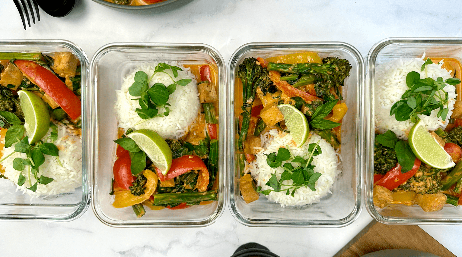 meal prep containers set up with a portion of rice, veggies, and crispy tofu